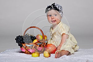 Infant girl near the basket with vegetables