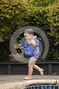 Infant girl running by the poo