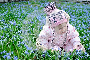 Infant girl sit snowdrops field