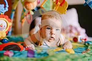 Infant lies on his tummy surrounded by soft toys and rattles