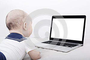 Infant lying down looking at the computer with copyspace