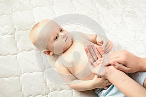 Infant nappy change and skin care. Mother makes massage for her baby and apply oil on the hands. stages of development of the