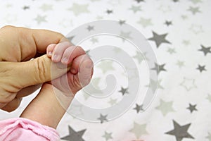 Infant, a newborn baby holding a mother`s finger closeup