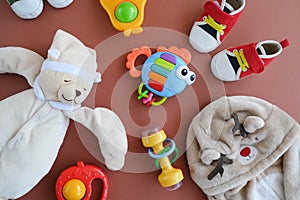 Infant `s goods. Plastic rattles, toy bear, cute shirt ant tiny sneakers. Flatlay design.