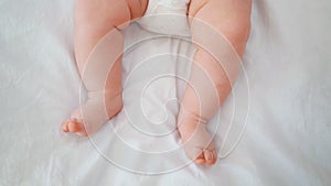 Infant's legs. The baby is lying on the bed and twitching his legs. Small feet. Newborn