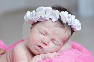 Infant sleeping in basket with accessory - head band, baby girl lying on pink blanket, cute child newborn