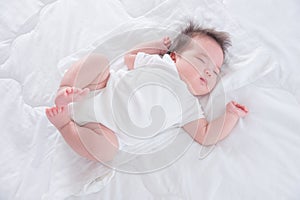 Infant sleeping on white bed in the morning
