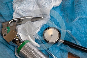 An infant stethoscope, orotracheal tube, and laryngoscope on white medical gauze and blue headcover.