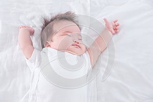 Infant stretching on white bed in the morning