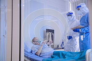 Infected patient lying on bed during takecare of Doctor and nurse with x-ray Lung in quarantine room