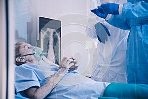 Infected patient lying on bed during takecare of Doctor and nurse with x-ray Lung in quarantine room