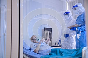 Infected patient lying on bed during takecare of Doctor and nurse with x-ray Lung in quarantine room photo