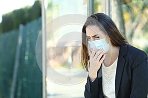 Infected woman wearing a mask coughing in a bus stop