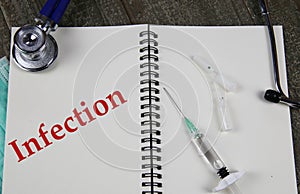 Infection control concept: View on open ringe file with white pages, single red word, stethoscope, syringe, vials photo