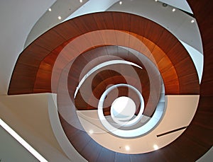 Concept of infinity. Multistory indoor atrium with suspended wood spiral stairs belly like camera shutter at USYD Business School