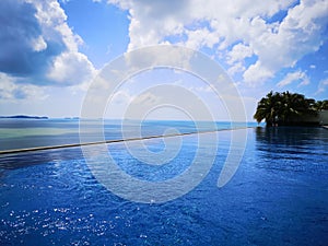 Infinity pool and ocean with blue sky and white clouds