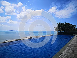 Infinity pool and ocean with blue sky and white clouds