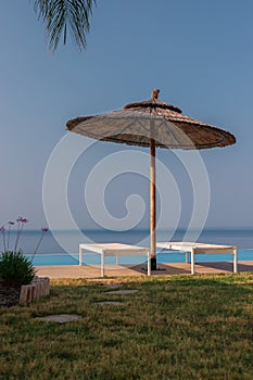 Infinity pool with sunbeds and umbrella.