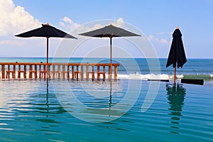 Infinity swimming pool with beach bar count, umbrellas and lounges