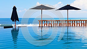 Infinity swimming pool with beach bar count, umbrellas and lounges