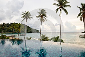 Infinity swimming pool modern luxury hotel, The hotel luxury swimming pool overlooks a wooden bridge that stretches out to the sea