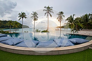 Infinity swimming pool modern luxury hotel, The hotel luxury swimming pool overlooks a wooden bridge that stretches out to the sea