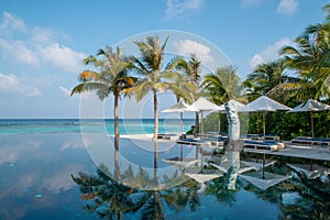 Infinity swimming pool near ocean and tropical beach view