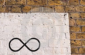 The infinity symbol drawn in black on a brick wall