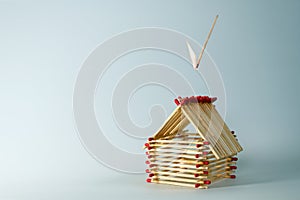 Inflamed match is falling on a house built of matches, light blue background with large copy space, insurance concept for real