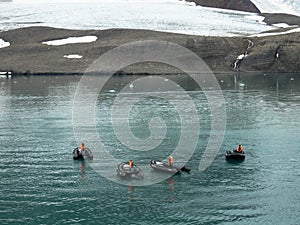Inflatable boats in front of a large glacier wall.