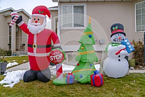 Inflatable Christmas decorations on a grassy yard with snow in winter
