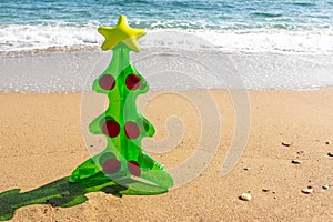 Inflatable Christmas tree on sandy beach. Creative Christmas or New Year concept