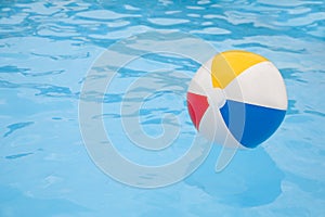 Inflatable colorful beach ball floating on water in swimming pool, space for text