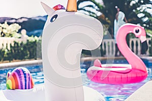 Inflatable colorful white unicorn and pink flamingo at the swim pool. Holidays time in the swimming pool with plastic