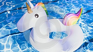 Inflatable colorful white unicorn at the swimming pool. Vacation time in the swim pool with plastic toys. Relaxation and