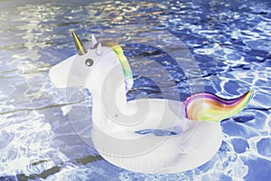 Inflatable colorful white unicorn at the swimming pool. Vacation time in the swim pool with plastic toys. Relaxation