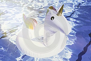 Inflatable colorful white unicorn at the swimming pool. Vacation time in the swim pool with plastic toys. Relaxation