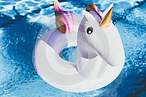 Inflatable colorful white unicorn at the swimming pool. Vacation time in the swim pool with plastic toys. Relaxation and