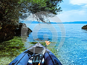 Inflatable kayak in a bay by the sea on a pebble beach. Canoe, sea coast with clear blue water on a sunny bright day in summer