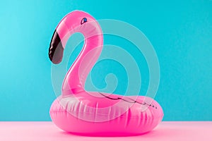 Inflatable mini flamingo on pastel blue and pink background. Pool float party, trendy summer concept. Flat lay, copy space.