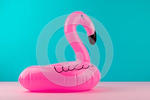 Inflatable mini flamingo on pastel blue and pink background. Pool float party, trendy summer concept. Flat lay, copy space.