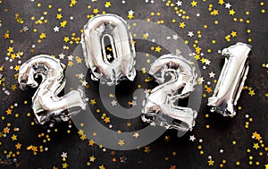 Inflatable numbers New Year 2021 on black background with shiny golden and silver stars. Copy space