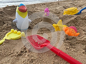 Inflatable penguin with various colorful toys on the beach sand for summer vacations