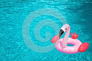 Inflatable pink flamingo in the blue water of swimming pool. Summer holidays, vacations, pool party, summertime heat idea