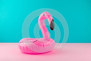 Inflatable pink flamingo on pastel blue and pink background. Pool float party, trendy summer concept.