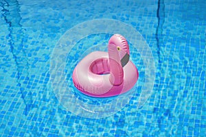 Inflatable toy of pink flamingo by blue water. Summer vacation holiday luxurious resort. pool party toy.