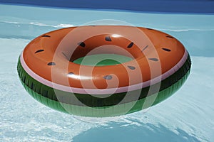 Inflatable watermelon ring in pool on sunny day