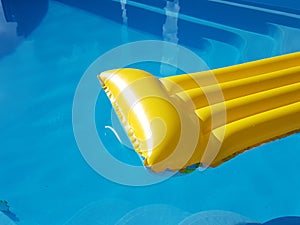 An inflatable yellow mattress floats in a blue pool with clear water. Rest on an artificial reservoir. Relaxation in the spa area