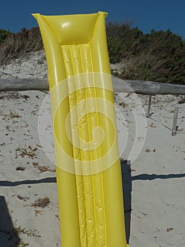 Inflatable yellow sunbed propped up on the sand