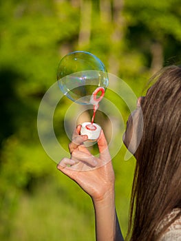 inflate big soap bubbles  girl inflates soap bubbles against the background